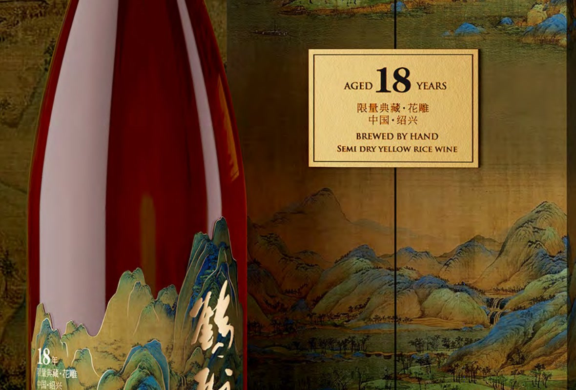 Landscape-format close-up of the gold plaque on the lid of the gift box, with part of the bottle and its blue-green landscape label at the left