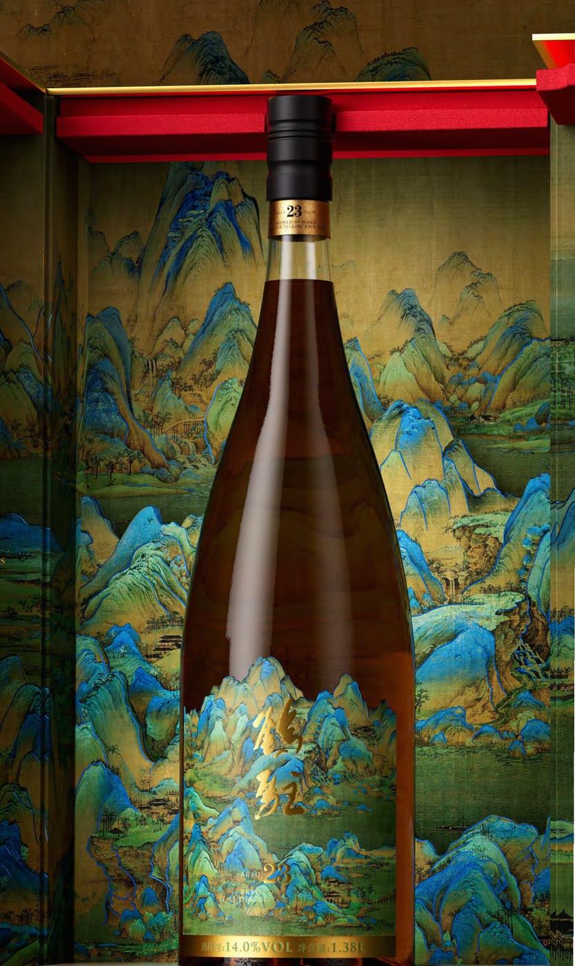 Close view of the bottle: a gold ring at the neck marked 23, a blue-green landscape and gold cursive script on the body, and another gold ring near the base